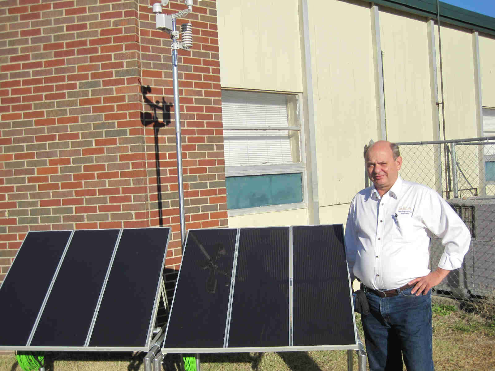 Dr. Bob stands by the assembled solar panel array with weather station installed.